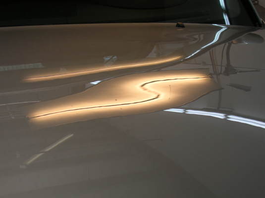 dent in Volvo hood before paintless repair 2